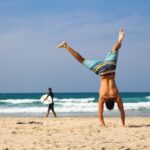 man doing a handstand on the beach