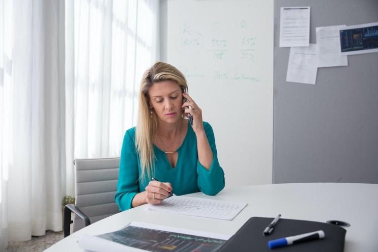 woman in a green blouse talking on the phone