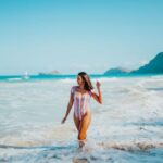 woman in a multicolored swimsuit walking on a beach