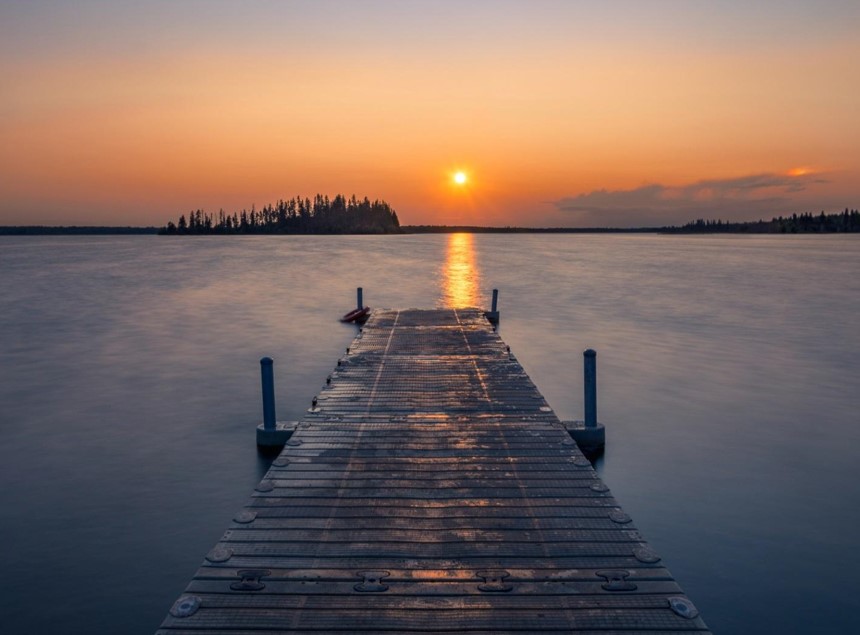 wooden dock in a lake during sunset