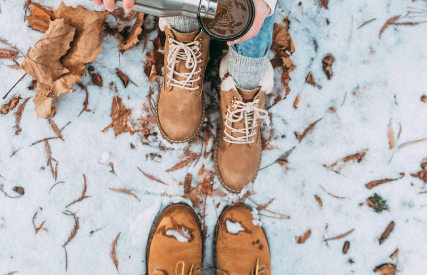 two women wearing boots and drinking coffee