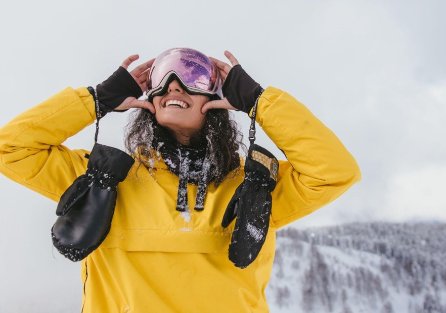 woman smiling and wearing ski goggles